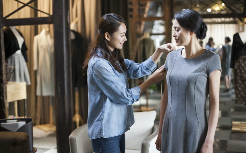 Fashion designer taking measurement of customer